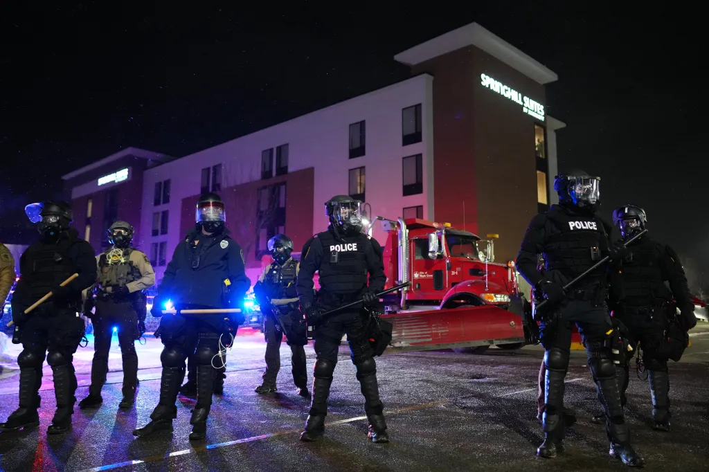 Law enforcement officers stand during a protest outside SpringHill Suites and Residence Inn by Marriott hotels on Monday, Jan. 26, 2026
