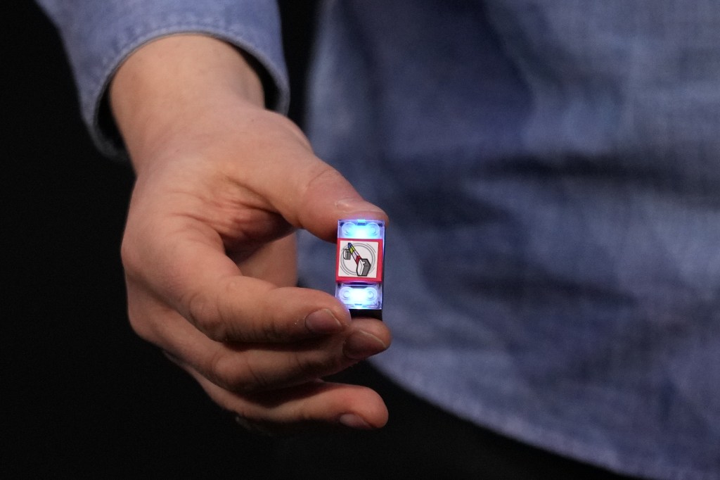 A person holding a glowing LEGO smart brick.