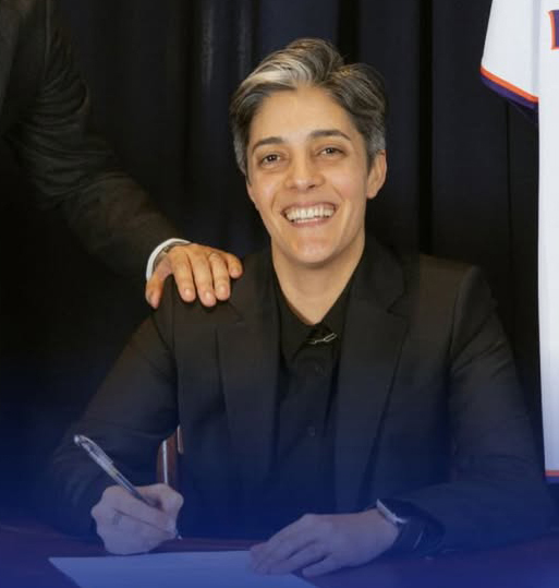 Leila Bozorg signing documents, with a hand on her shoulder.