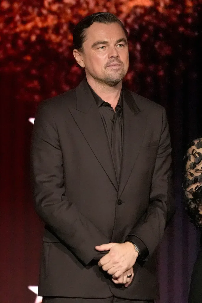 Leonardo DiCaprio in a black suit with his hands clasped in front of him.