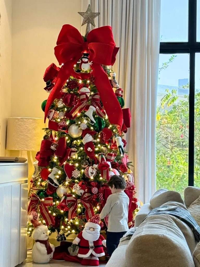 Lindsay Lohan's son Luai standing in front of a decorated Christmas tree.