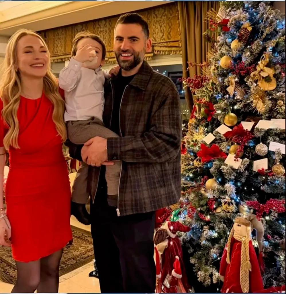 Lindsay Lohan, husband Bader Shammas, and son Luai posing in front of a Christmas tree.