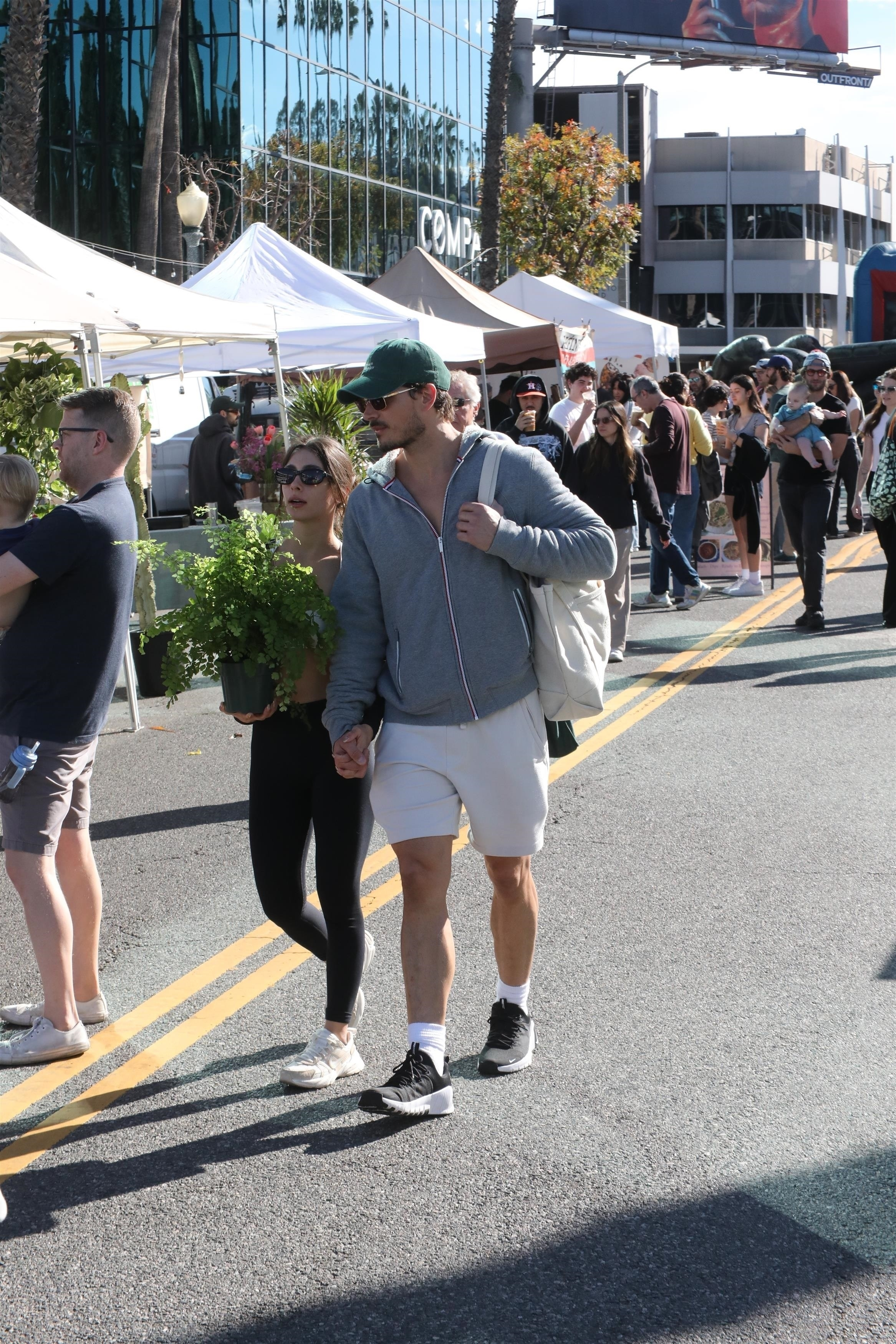 Gleb Savchenko holding hands with Elena Belle while walking through a market.