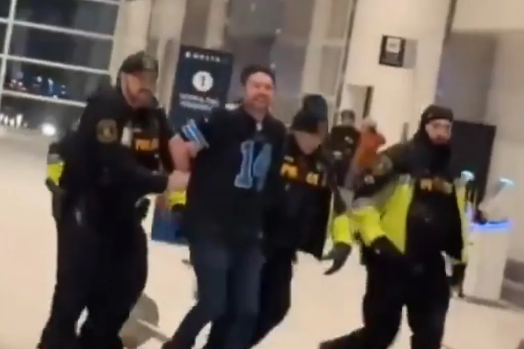 Police officers arresting a man inside an airport terminal.