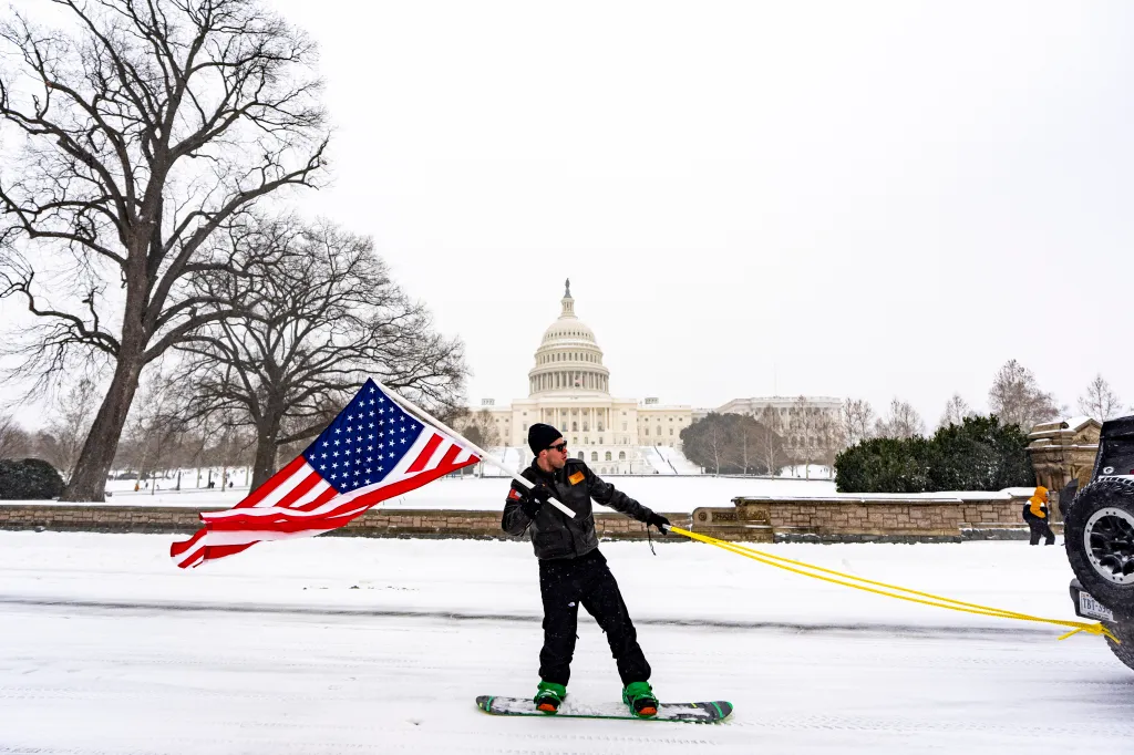 A man riding a snowboard near the Capitol building in Washington, DC.