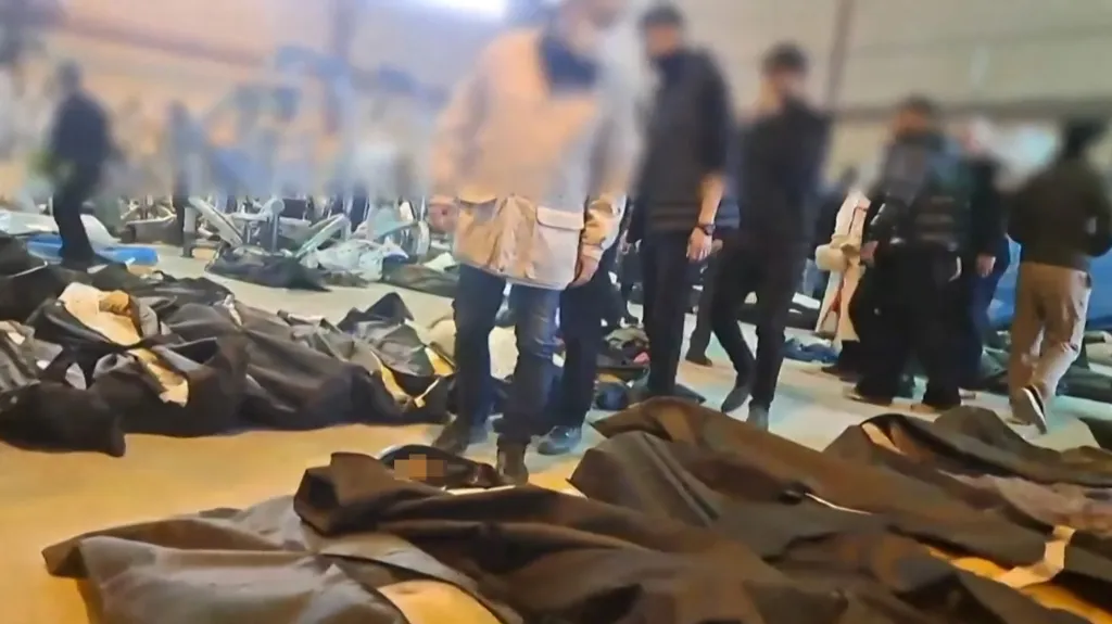 Mourners walk among body bags in a forensic center.