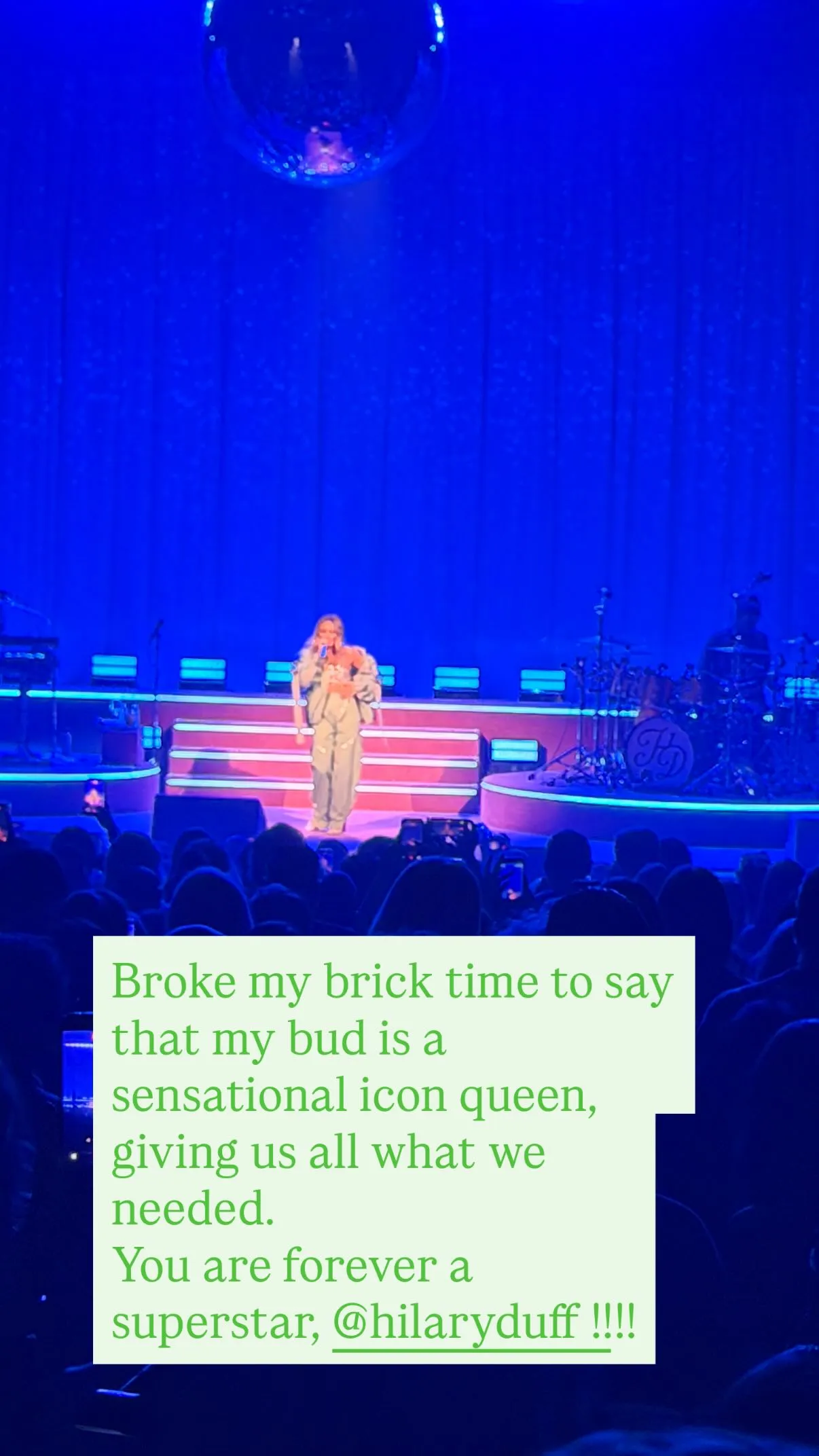 Hilary Duff performing on stage, seen from the perspective of an audience member with an overlaid text praising her performance.