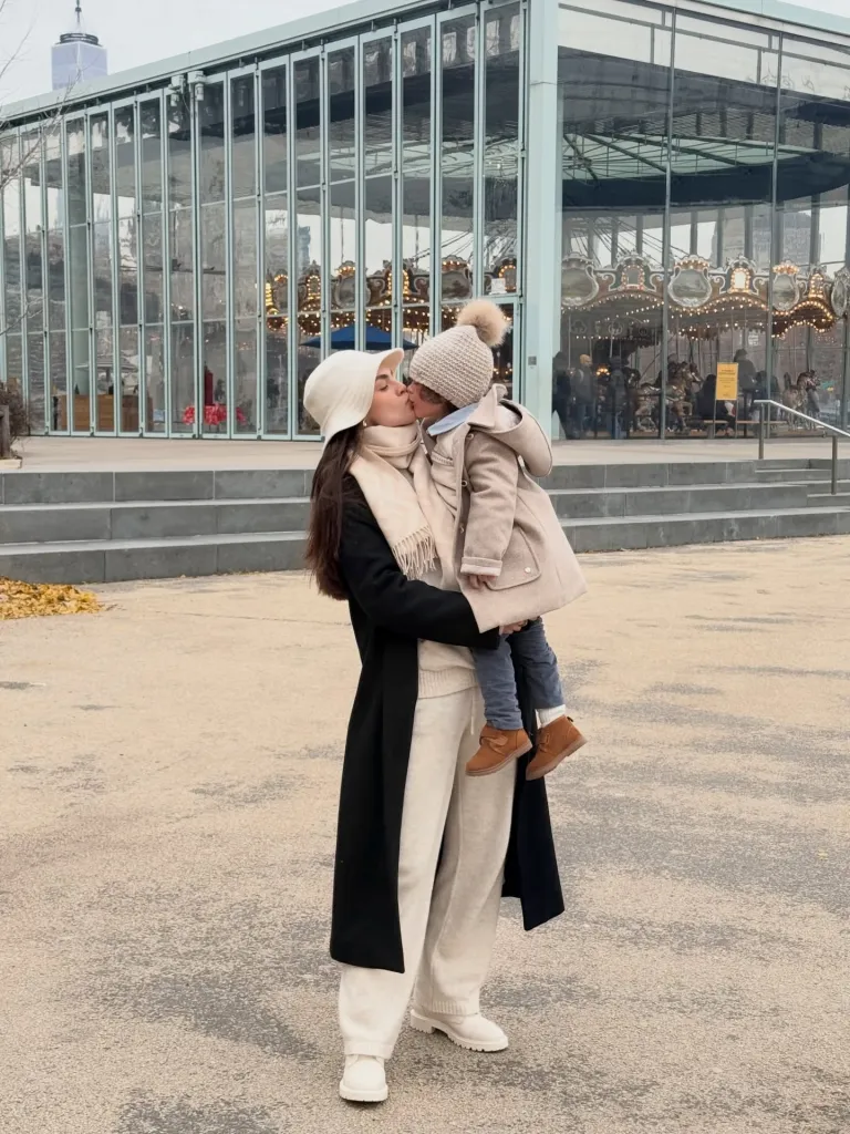Nadia Ferreira kissing her son in front of a carousel.