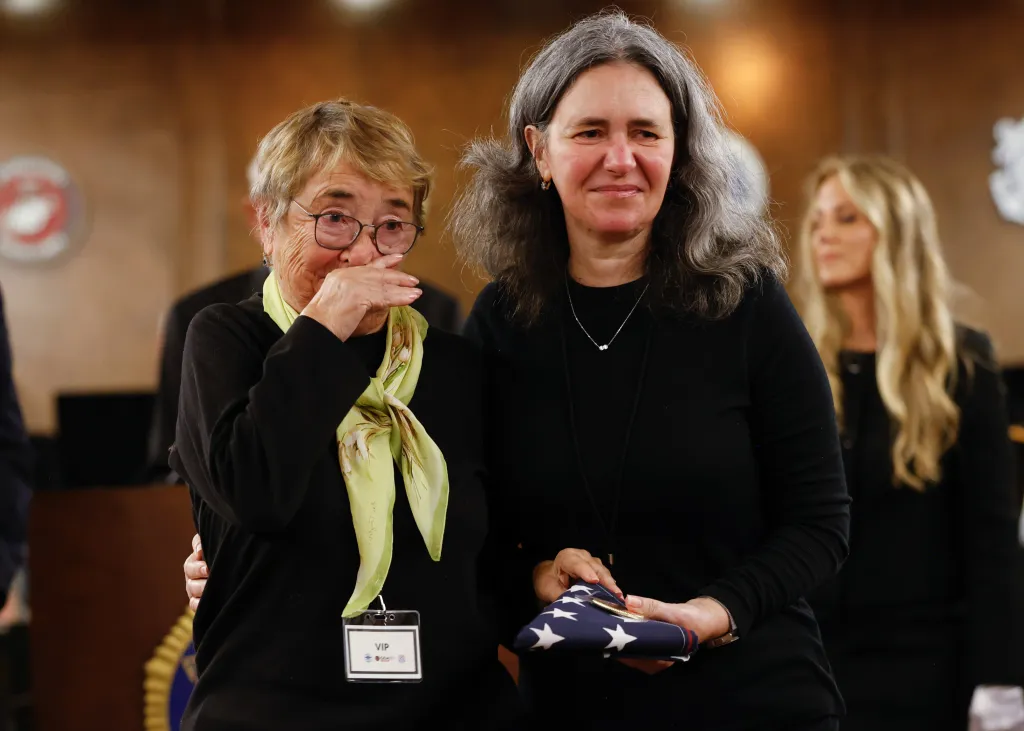 Marina Ahterrnberg (left) and Maya Amanda (right) receive a flag for a lost loved one during the Palisades fire.
