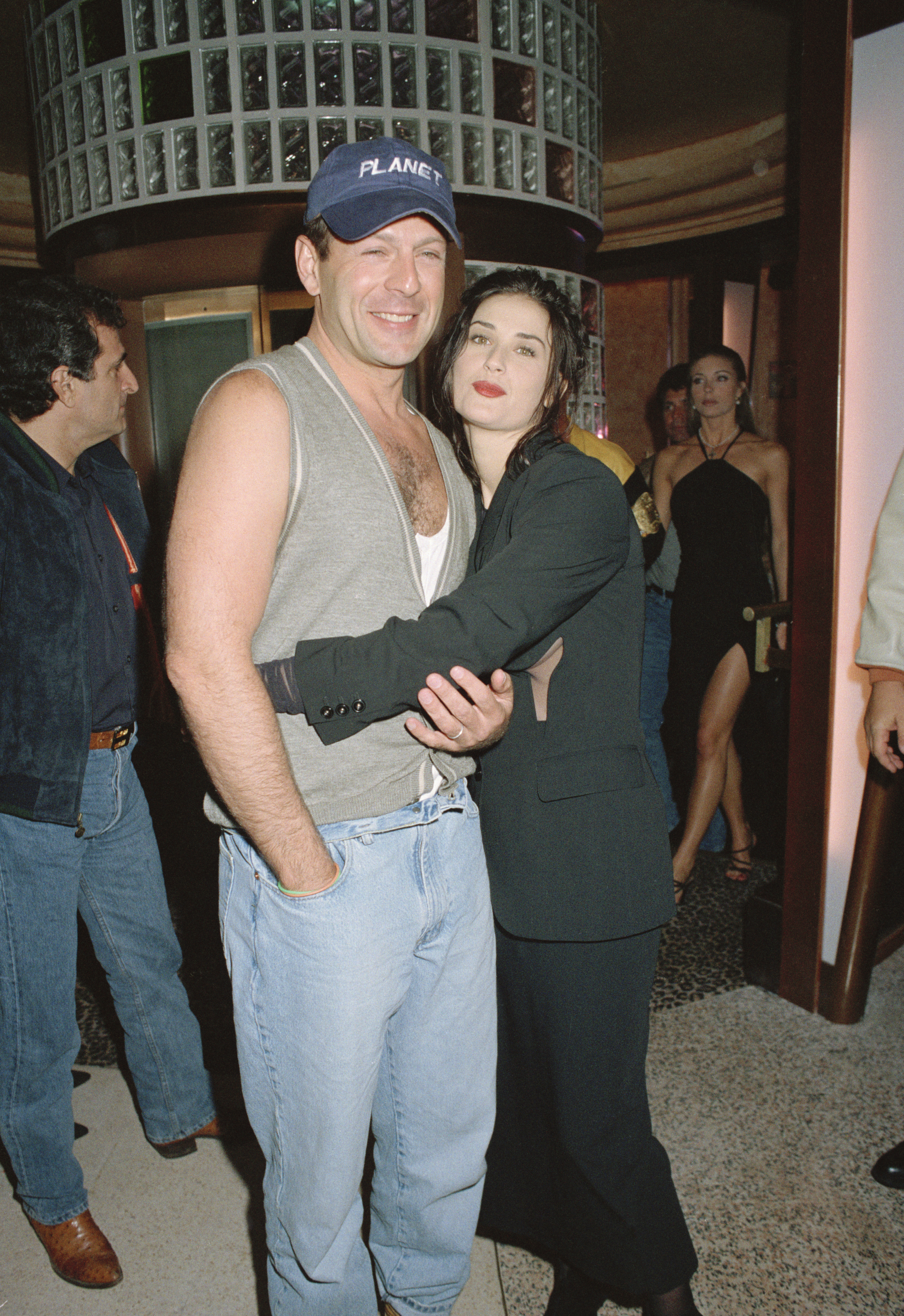 Bruce Willis smiling and embracing Demi Moore at the opening of Planet Hollywood in London.