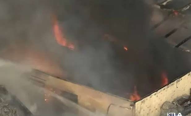 Commercial building engulfed in flames and thick black smoke.