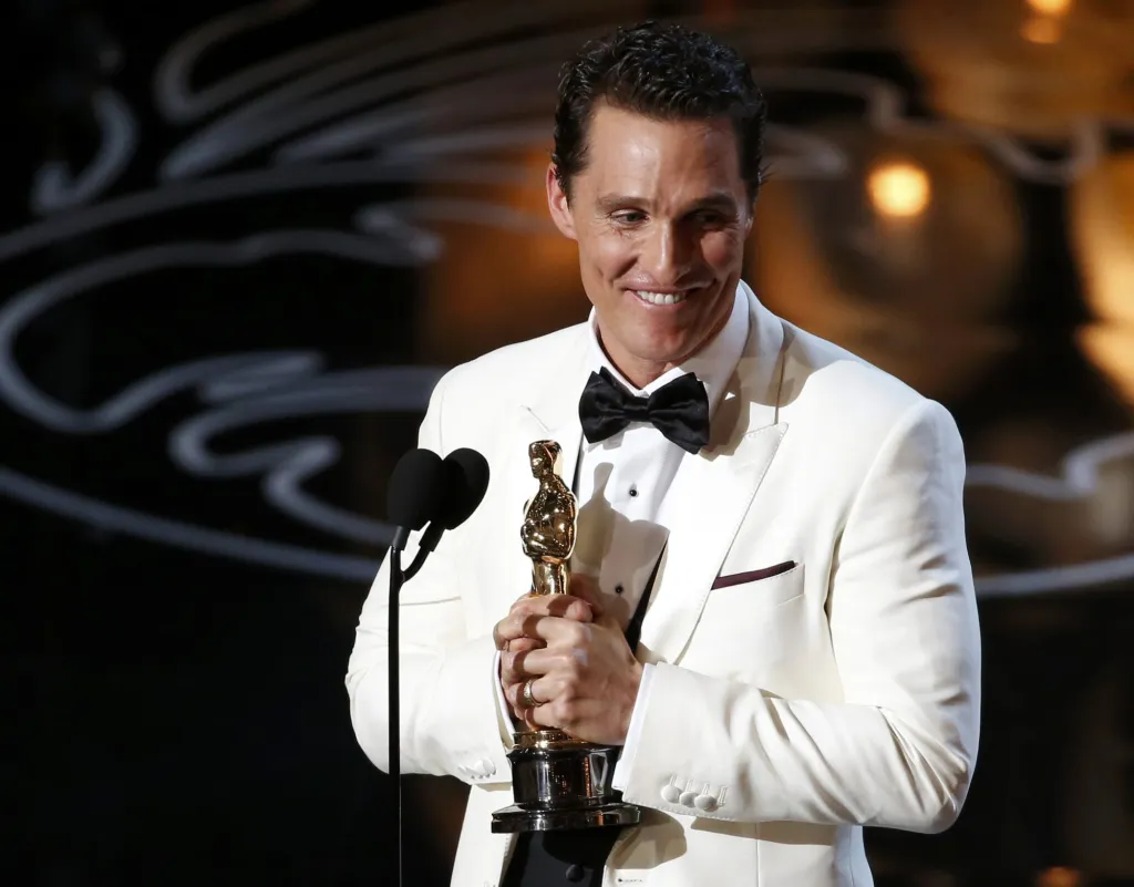 Matthew McConaughey in a white suit accepting the Oscar for best actor trophy at the 86th Academy Awards in Hollywood