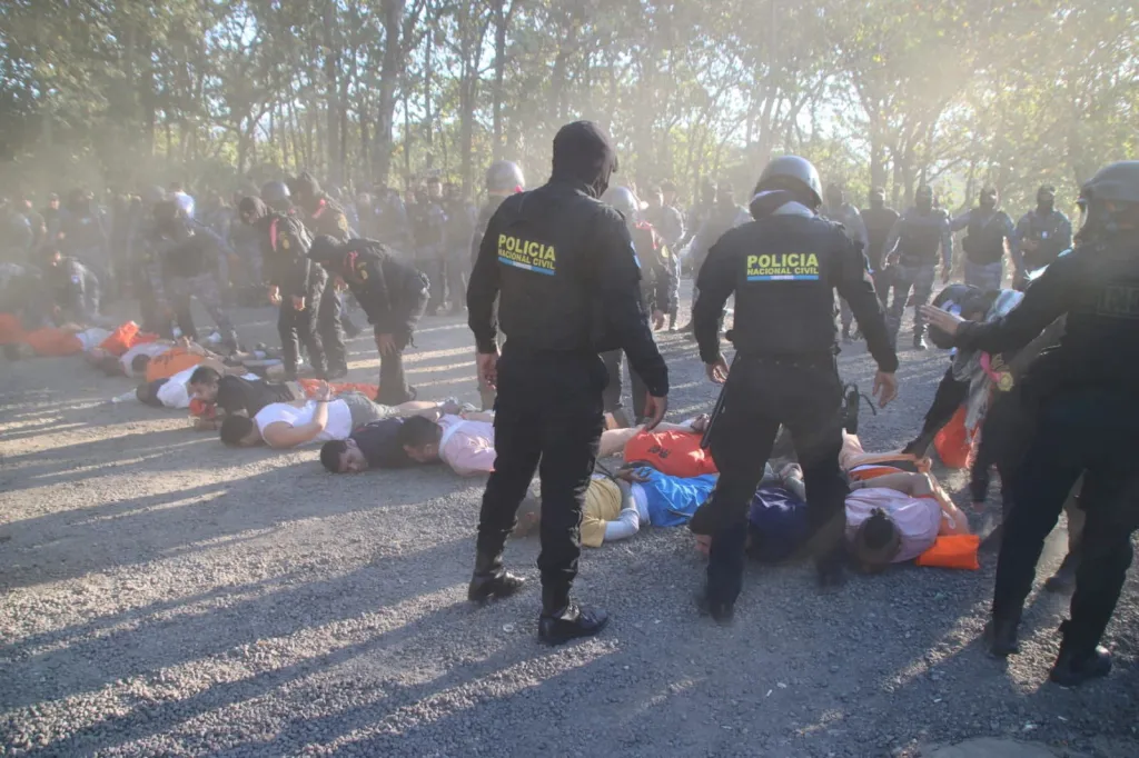Members of the National Civil Police stand over retaken inmates lying on the ground.
