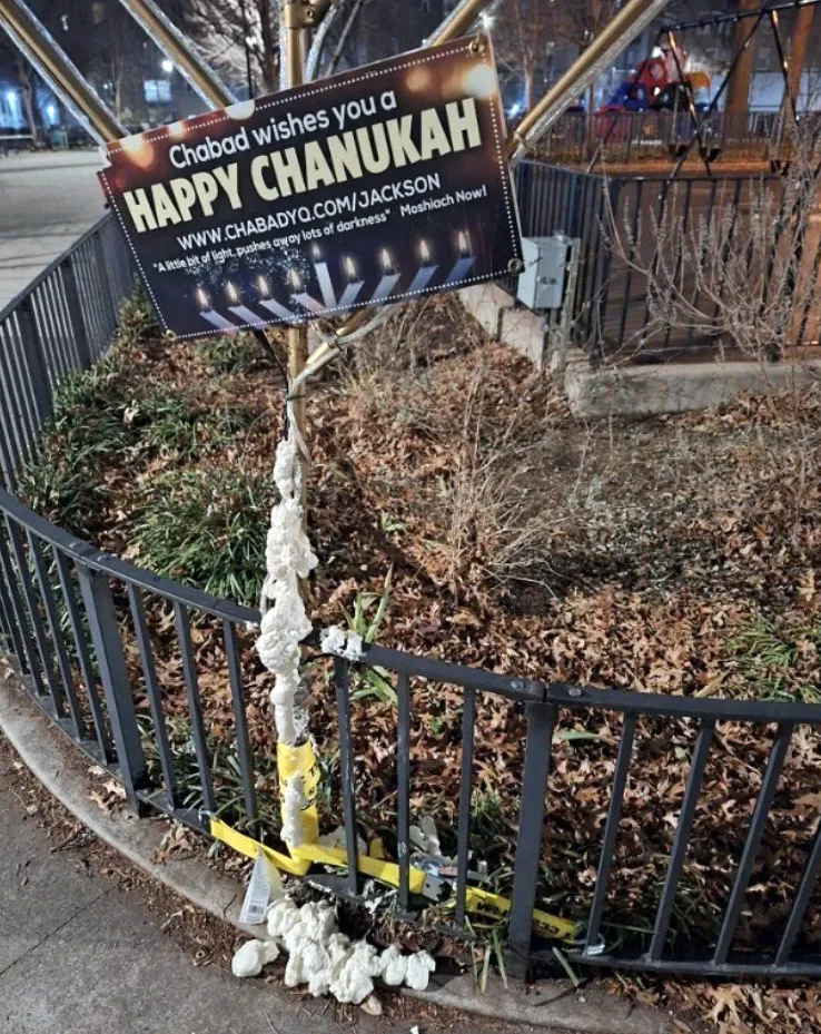 A menorah in a park, covered in white spray foam, with a 