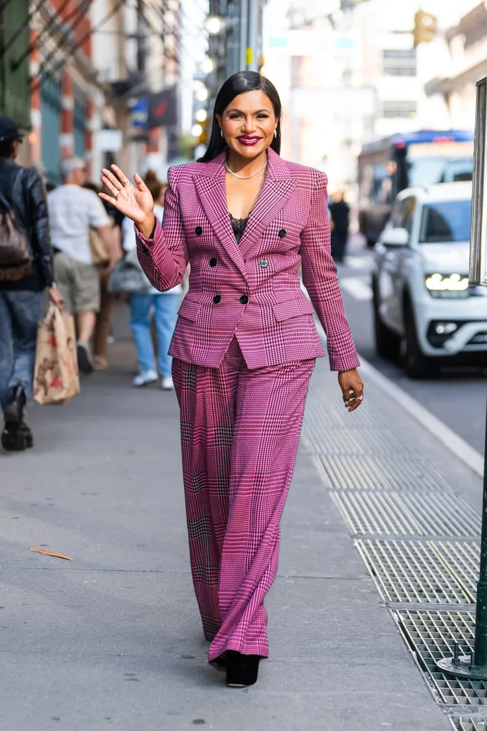 Mindy Kaling walking in SoHo in a pink plaid pantsuit.