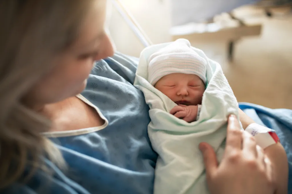Mother holding her newborn baby swaddled in a hospital.
