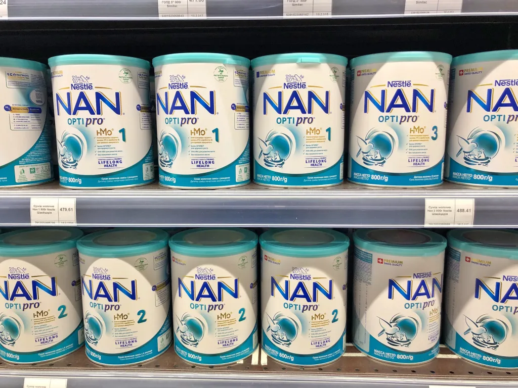 A supermarket shelf stocked with multiple cans of Nestle NAN OPTIPRO baby milk formula.