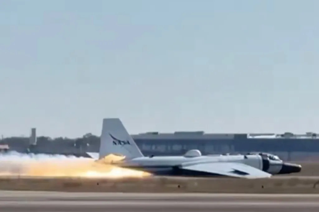 NASA plane making a belly landing with flames and smoke visible under its fuselage.