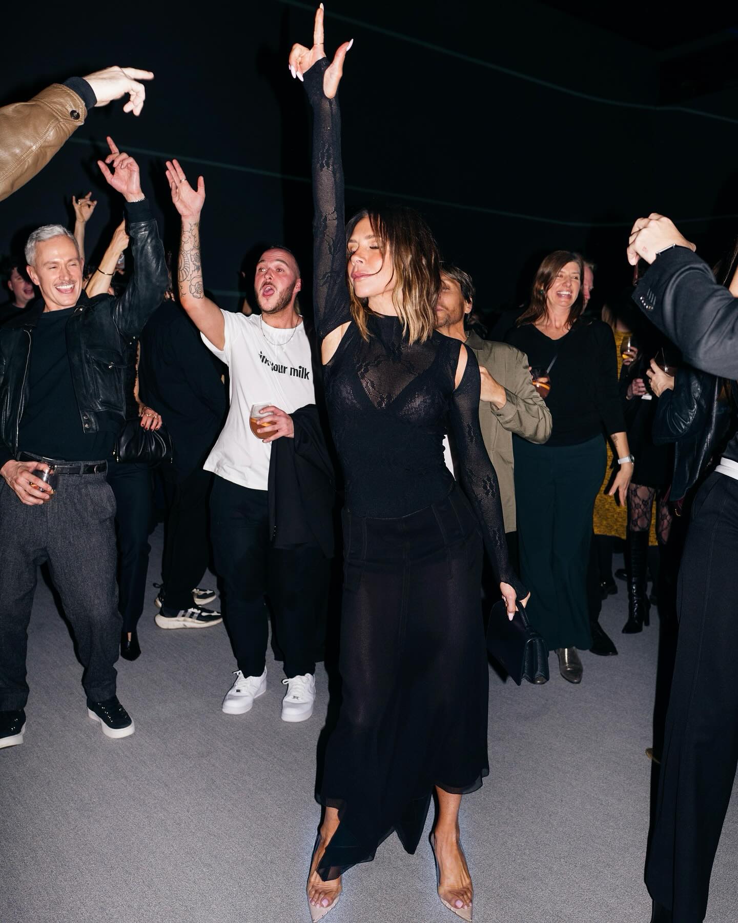 Victoria Beckham dancing with a raised hand at a party.