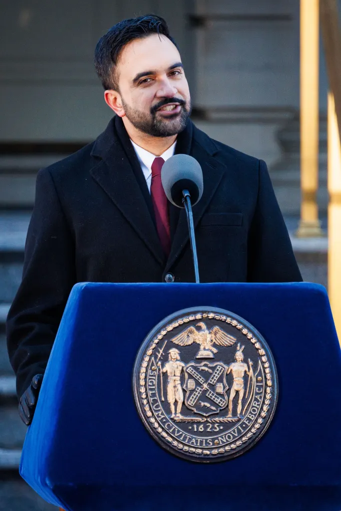 New York City Mayor Zohran Kwame Mamdani speaking at a podium with the New York City seal.