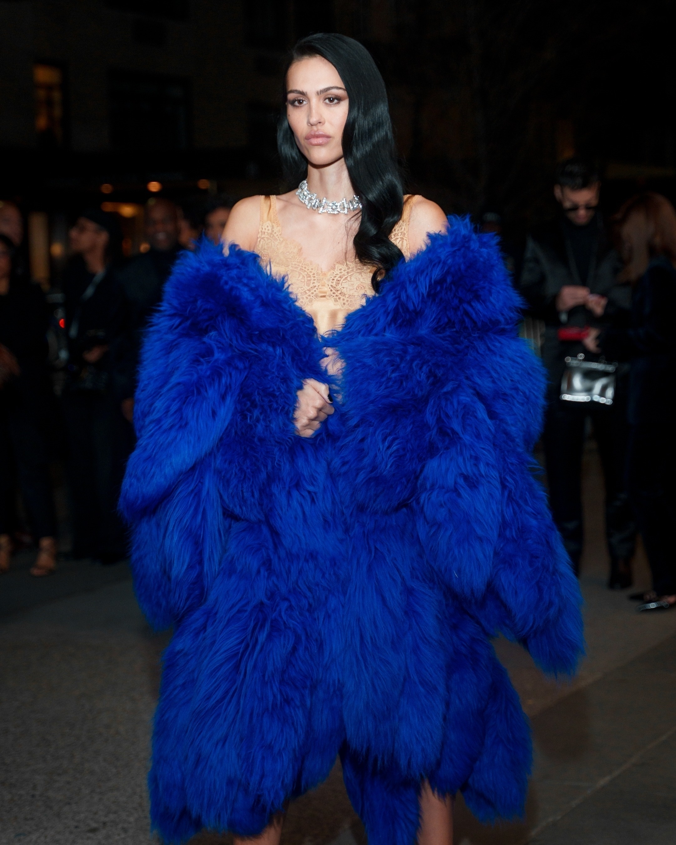 Amelia Gray Hamlin at the FX “The Beauty” premiere in New York, wearing a large blue faux fur coat over a beige lace top, and a sparkling choker necklace.