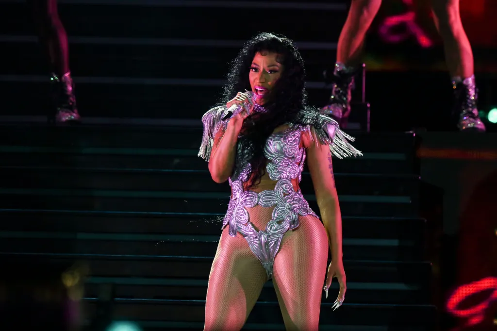 Nicki Minaj performing at Rolling Loud, wearing a sparkly silver bodysuit and holding a microphone.