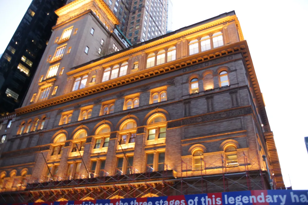 Carnegie Hall building with a blue banner below scaffolding.