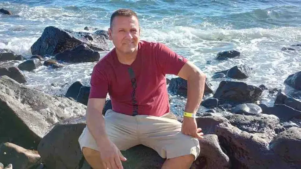 Jose Fernando Partida sitting on rocks by the ocean.
