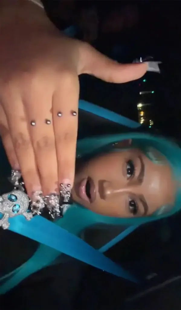North West with teal hair, a skull necklace, and fingernail piercings.