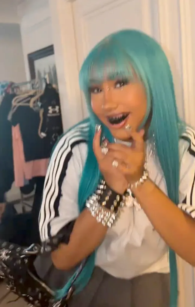 North West with a blue wig, bridge piercing, blacked-out teeth, and a diamond pendant.