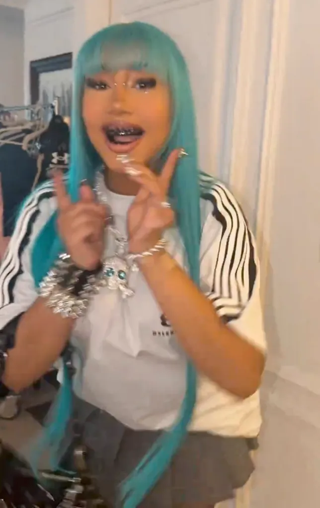 North West wearing a blue wig, bridge piercing, black teeth, and diamond pendant.