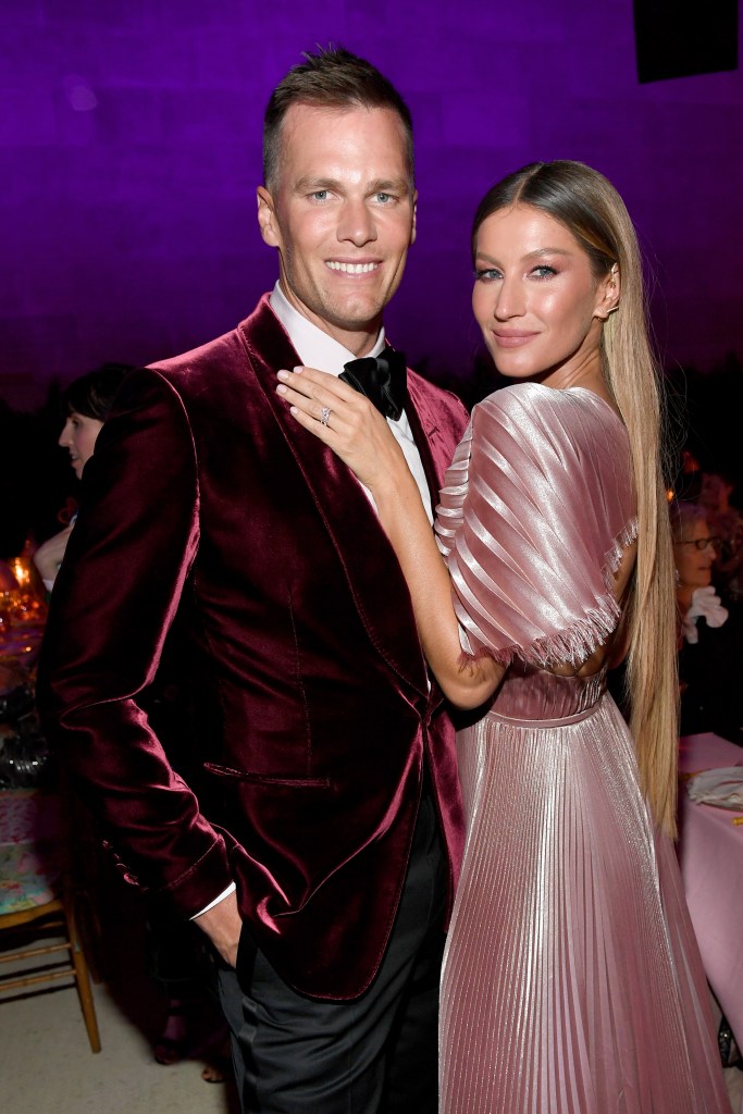 Tom Brady in a red velvet suit and Gisele Bundchen in a pink pleated dress.