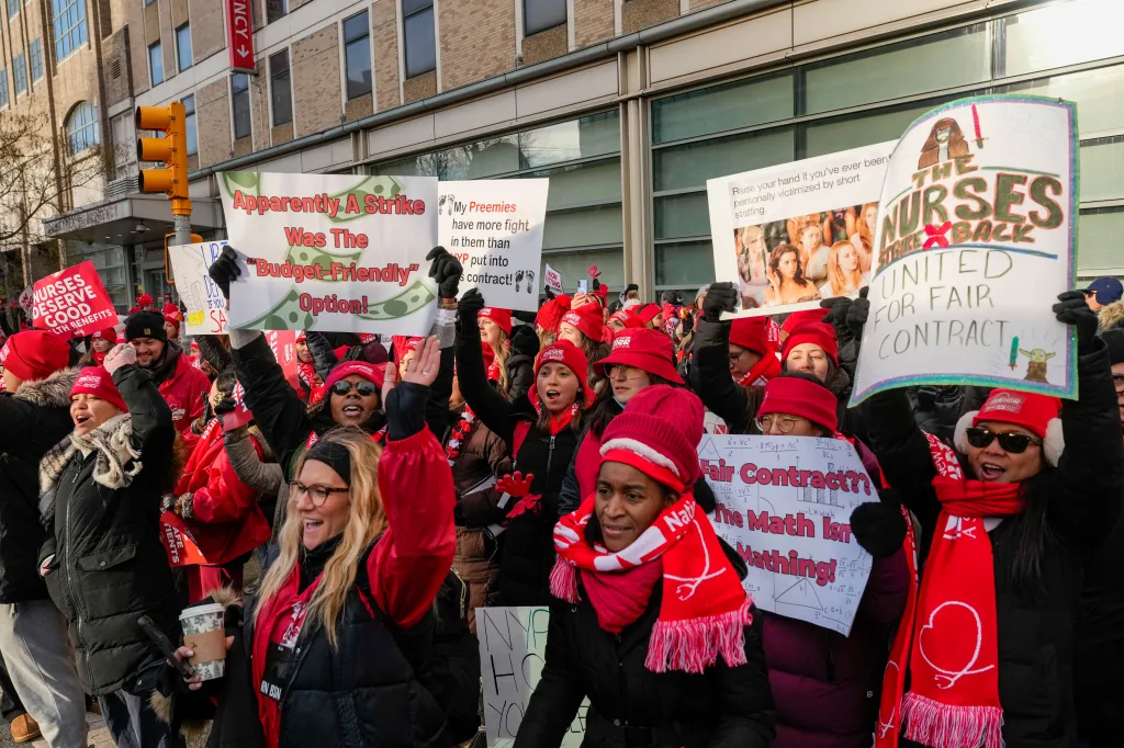Nurses on strike in New York City hold signs in protest.