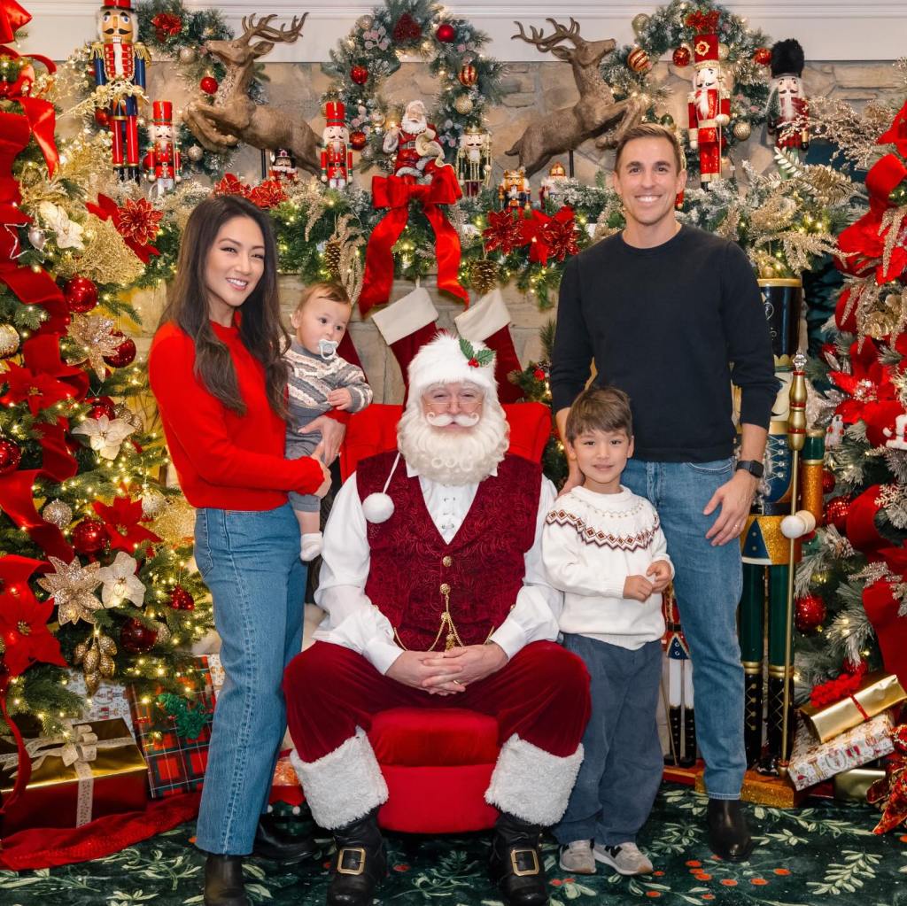 Family posing with Santa Claus in front of a Christmas fireplace.