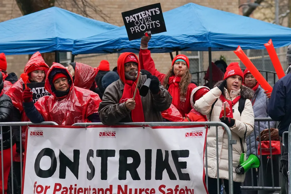 nurses under blue tents and banners saying on strike