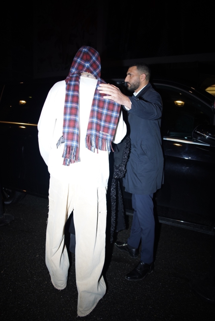 Romeo Beckham leaving a party in Paris with a man guiding him to a vehicle.