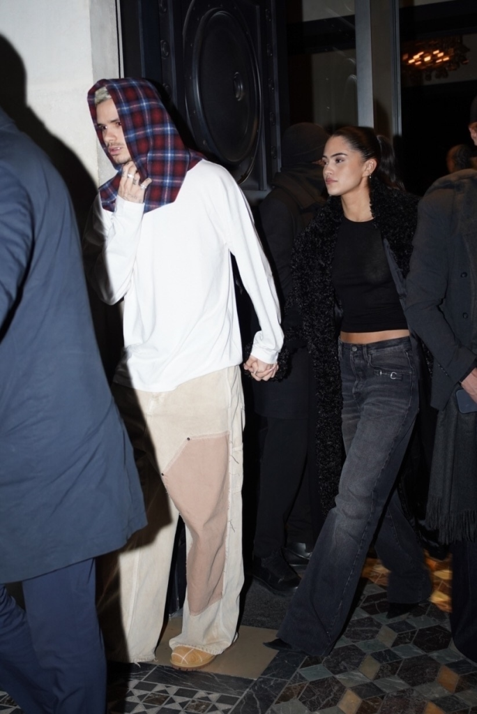 Romeo Beckham wearing a plaid hood and Kim Turnbull in a furry jacket leaving the Costes Hotel party in Paris.