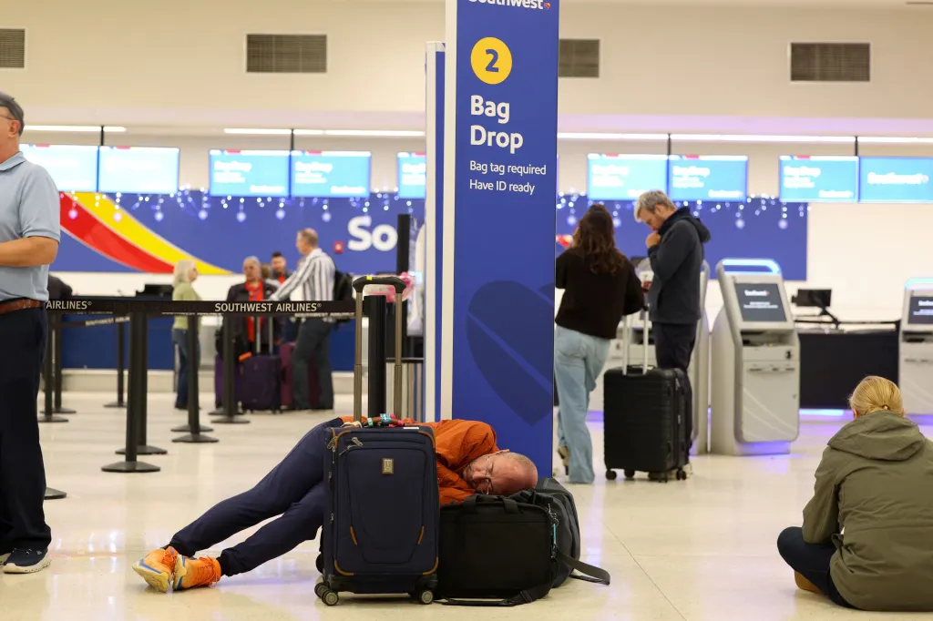A passenger sleeps on his luggage after flights were delayed and cancelled because of closed airspace at Rafael Hernandez International Airport on Jan. 3, 2026.