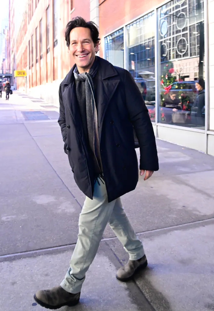 Paul Rudd smiling while walking on a city sidewalk.