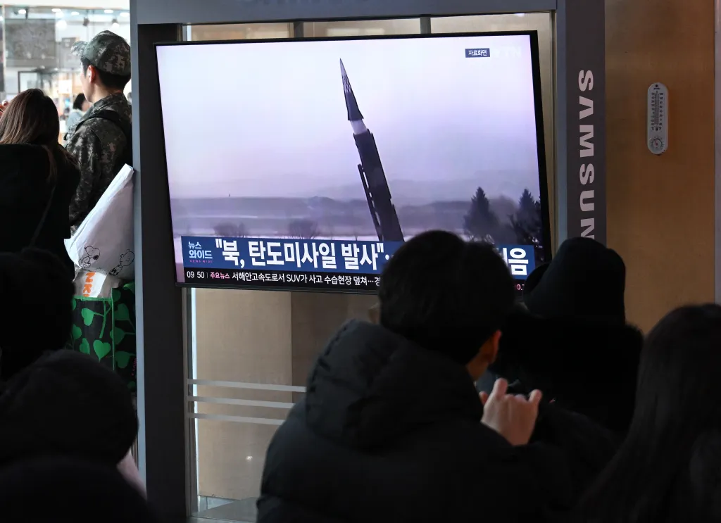 Train passengers watch file footage of a North Korean missile test on a television at a station in Seoul on Jan. 4, 2026.