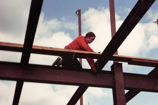 Arthur Roy Simoneau working on a steel beam structure under a partly cloudy sky.