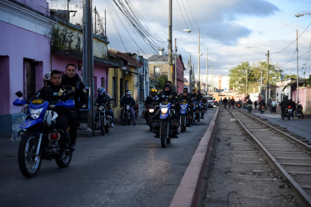 Police officers on motorcycles patrol a street in Guatemala City.