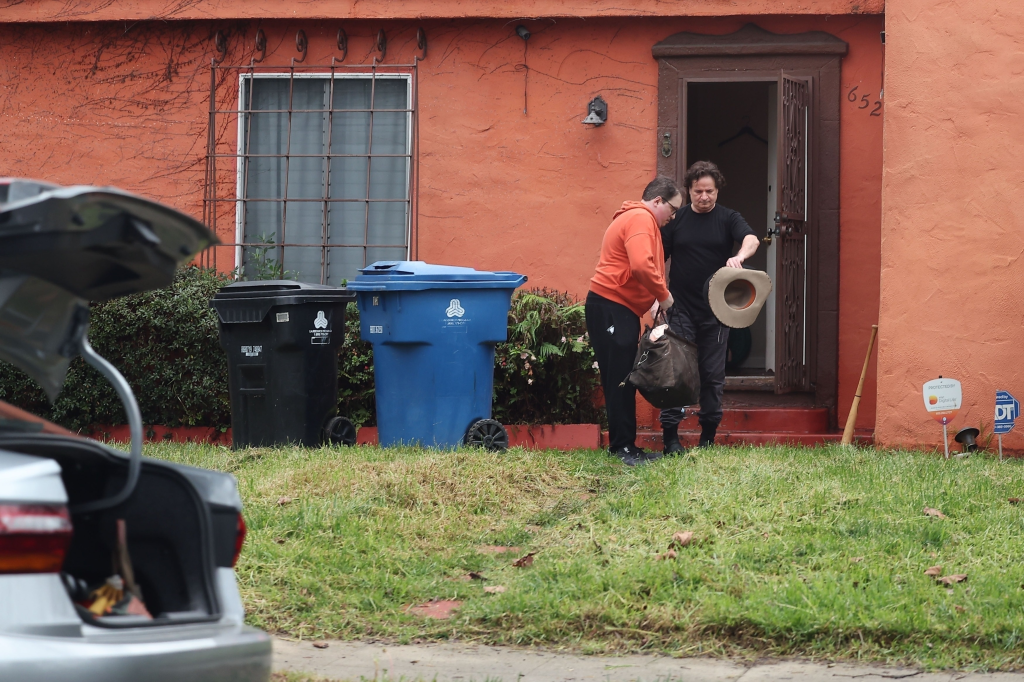 Mickey Rourke and a friend load luggage and a dog into a car.