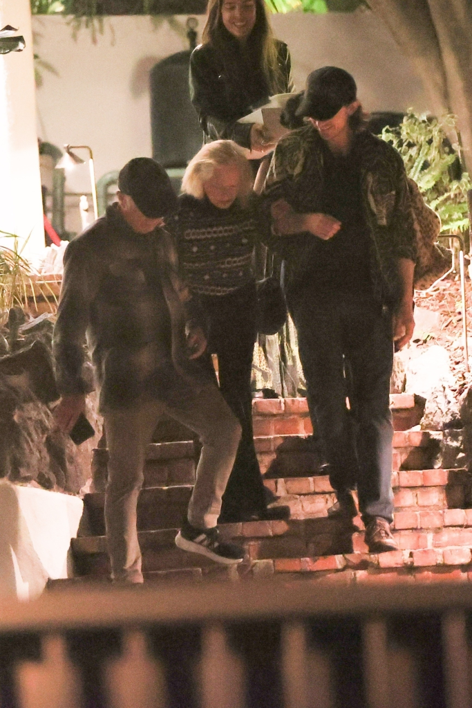 Tippi Hedren, assisted by Melanie Griffith, descends outdoor stairs at night.