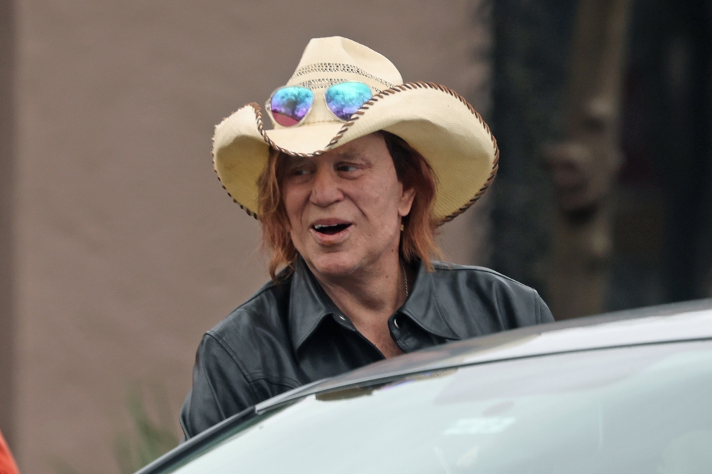 Mickey Rourke in a straw cowboy hat with mirrored sunglasses perched on the brim.
