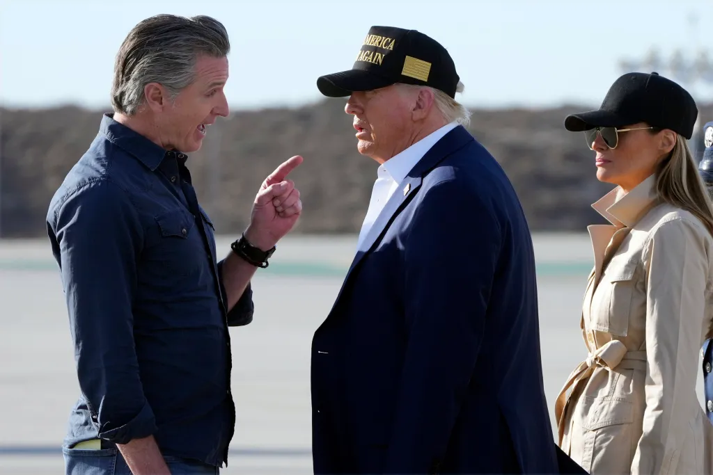California Governor Gavin Newsom pointing and speaking to President Donald Trump, with Melania Trump standing beside Trump.