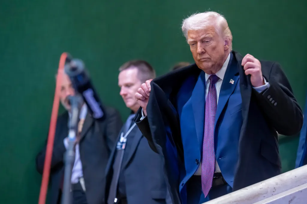 President Donald Trump walking down stairs while adjusting his coat.