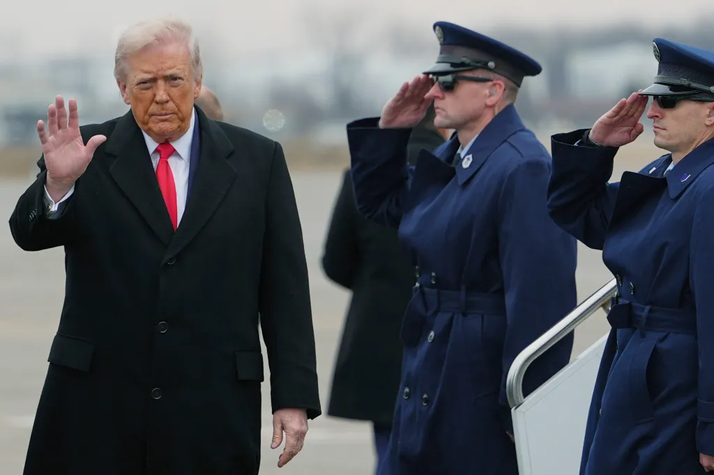 President Donald Trump waves while two men in military uniforms salute.