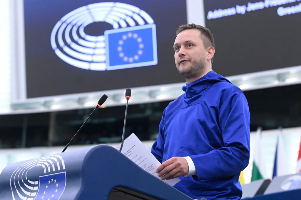 Jens-Frederik Nielsen, Prime Minister of Greenland, speaking at a podium with two microphones, with the European Parliament logo visible behind him.