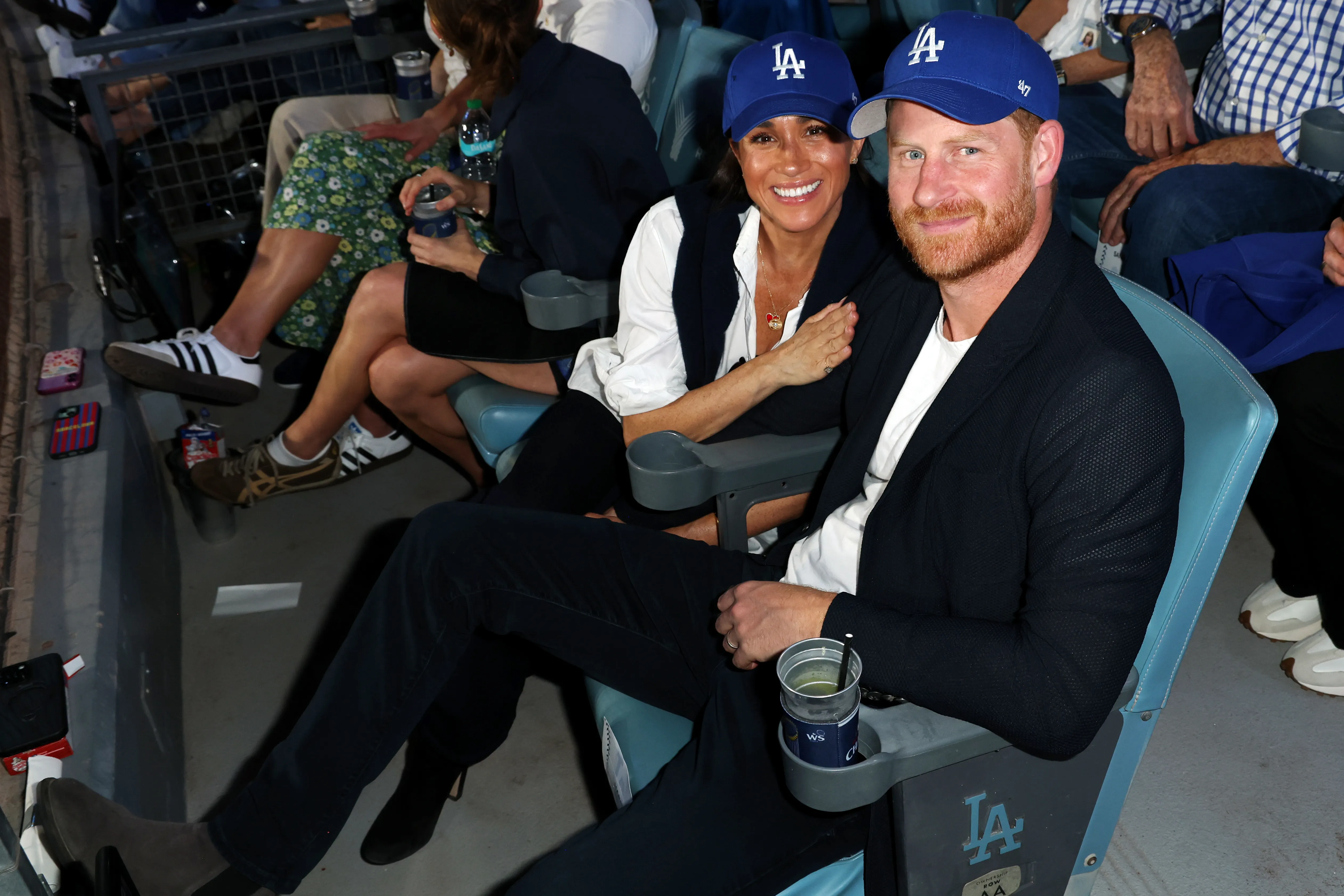 Prince Harry and Meghan, Duchess of Sussex, pose for a photo at a baseball game.